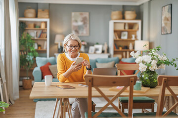 Smiling woman in cozy living room checking her phone while enjoying a peaceful morning at home with coffee and fresh flowers