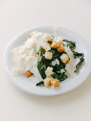 Fresh salad with creamy dressing, croutons, and shredded cheese served on a white plate