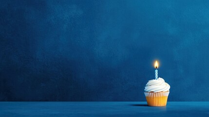 Single cupcake with bright frosting and a lit candle on a minimalist blue background perfect for birthday celebrations and festive occasions