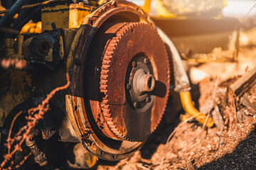 Abandoned old yellow tractor motor. Sunny sky in background. Old motor wreck.