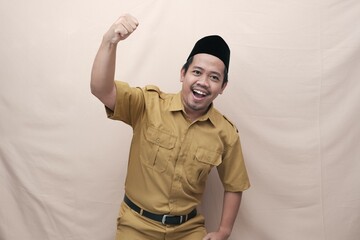 Excited Indonesian government worker man wearing khaki uniform posing with a happy successful...