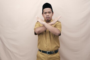 Young Asian government worker man wearing a brown uniform shows crossed hands or stop gesture,...