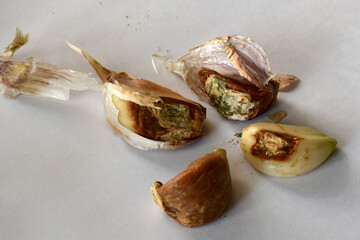 a group of garlic cloves with brown sores and rot spots on a blurred background. Selective focus. Damaged, spoiled garlic, unsuitable for eating and planting