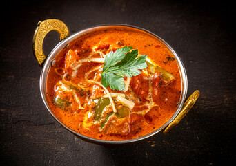 Chicken Tikka Masala  Indian cuisine dish of Boneless Chicken marinated in yogurt, with spices, ginger, garlic, chili, spices,   onions and peppers, on a dark wood background