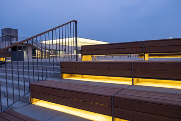 Wooden step and seating with lighting underneath, with metal handrail on the side