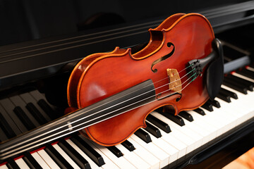 Fototapeta premium Violin on top of piano keyboard background with copy space for music concept or orchestra concert performance.