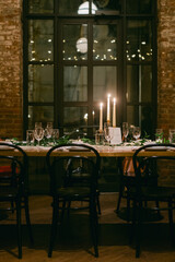 Elegant dinner table set with candles and glasses in a cozy, warmly lit venue on a quiet evening