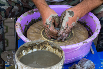 Hands of a potter, creating an earthen jar on the circle.