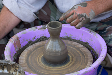 Hands of a potter, creating an earthen jar on the circle.