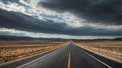 A long, empty road stretching through a barren, hilly landscape under a cloudy sky