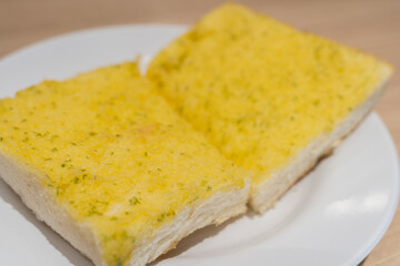 Garlic bread served on a white plate is a delicious and visually appealing dish.