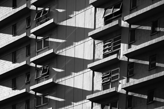  High contrast architectural fine art abstraction. A black-and-white photograph of a building facade, emphasizing geometric patterns and shadows. 