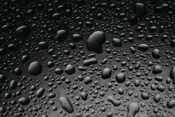 Water drops on dark grey glass surface, closeup