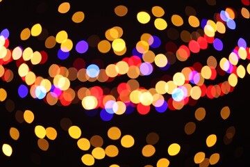 Blurred view of colorful lights on black background, bokeh effect