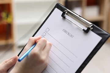 Woman filling Checklist with pen indoors, closeup