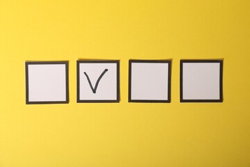 One checkbox with tick mark among others on yellow background, flat lay