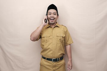 Smiling Indonesian government worker man wearing khaki uniform while talking on the phone. PNS ASN...