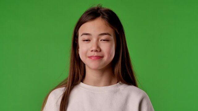 Asian girl child posing at camera with confused clueless face, shrugs and holds hands up, positive expression, isolated on chroma key green screen background mockup.