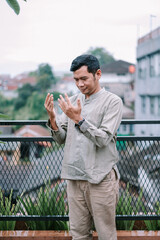 Young Muslim man sincerely praying, seeking guidance and blessing outdoors