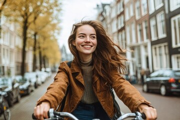 Happy female tourist visiting Amsterdam city, Netherlands - Delightful woman riding bicycle in urban street - Holidays, traveling and transportation life style concept