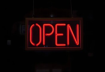 Illuminated neon open sign outside lit up at night on a shop window to advertise that the retail outlet is serving.
