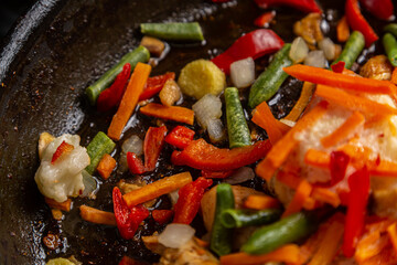 Bright multi-colored vegetables stewing in a frying pan close-up