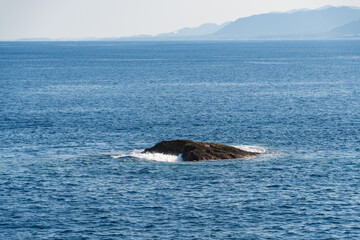 Fototapeta premium 海に浮かぶ孤岩と波の風景