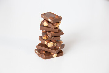 pieces of chocolate with nuts are folded one by one in a pyramid on a white background