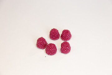 Five pink jelly candys in the shape of a raspberry on a white background