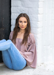 Portrait of a young beautiful brunette girl in blue jeans posing in a stone arch