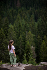 A teenage girl standing on a cliff or a mountain