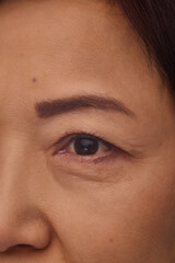Fototapeta premium Close-up of Korean mature woman face, eye, eyebrow and cheeks. Healthy glow, soft skin texture, anti-aging skincare products. Concept of facial rejuvenation, wrinkle treatment, cosmetology