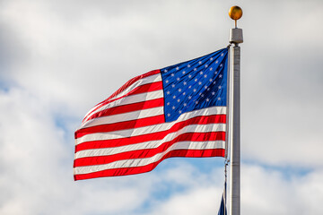 American flag waving with clouds in the background