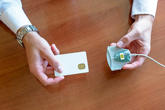 A close-up of a person inserting a smart card into a card reader for authentication. Secure digital access concept in an office environment.