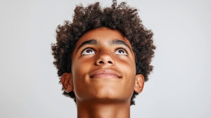 Portrait of a young afro man looking up on a white studio background.