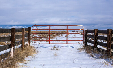 Red metal gate leading to farmland