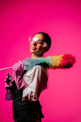 Portrait of a female cleaner showcasing her tools against a vibrant pink background in a clean and modern setting