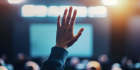 Audience Hand Raised to Ask Question During Conference Presentation with Blurred Background and Soft Lighting Effects