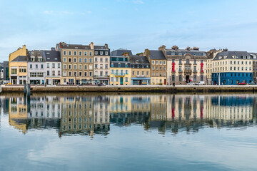 A view of shoreline buildings reflected in the water of the inner harbor  at Cherbourg, France in...