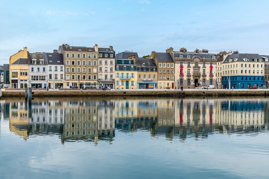 A view of shoreline buildings reflected in the water of the inner harbor  at Cherbourg, France in autumn