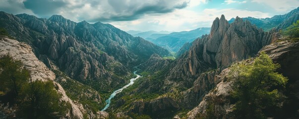 Majestic mountain valley with dramatic cliffs and serene river under cloudy sky