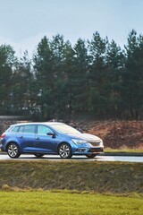 Blue wagon driving with woods background