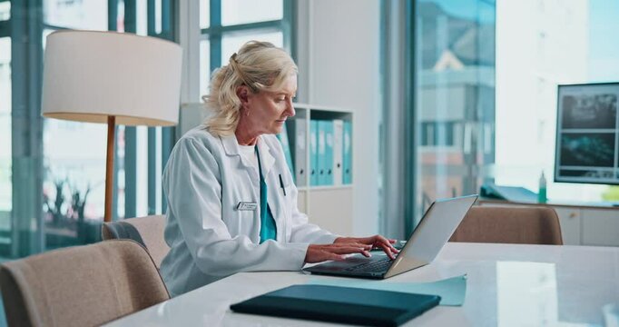 Doctor, smile and typing with laptop in office for telehealth, medical report and hospital administration. Mature person, radiologist and database archive for healthcare research and treatment plan