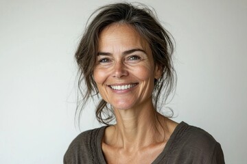 Obraz premium Portrait of a confident mature woman smiling with natural beauty, showcasing a relaxed and authentic lifestyle against a simple, clean backdrop, displaying grace.