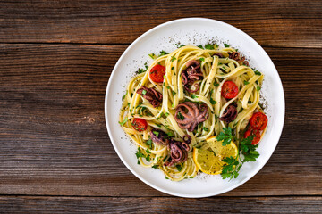 Pasta with baby octopus on wooden table	