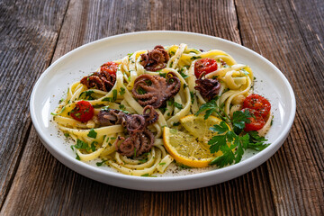 Pasta with baby octopus on wooden table	