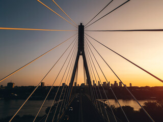 modern metal cable bridge over Vistula river at sunset, contemporary geometric architecture, cable-stayed bridge at city skyline, symmetry and architectural urban contrast, Warsaw