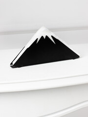 Stylish napkin holder designed in the shape of a mountain with a black base and white snow-capped peak.