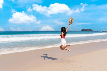 Happy young Asian female relaxing around beautiful tropical sea beach ocean with white cloud on blue sky in travel vacation. Summer and holiday concept. Copy space