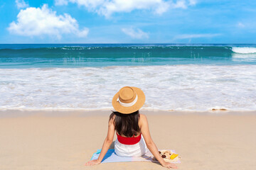 Carefree young Asian traveler female in red swimwear and shorts relaxing at tropical sandy beach with beautiful blue sky. Summer vacation concept. Copy space